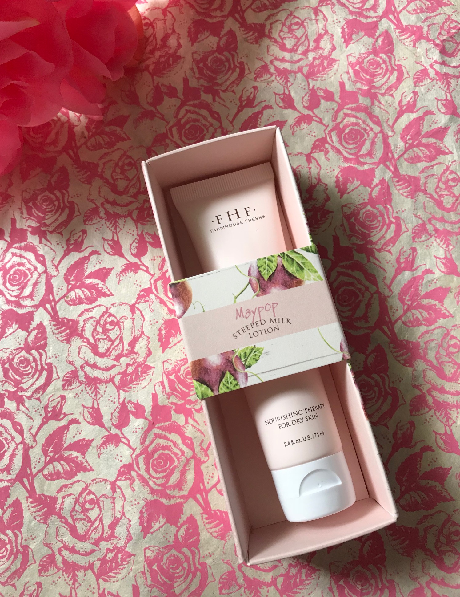 outer box illustrated with passion fruit on a pale pink background with the pink tube of Farmhouse Fresh Maypop Steeped Milk Lotion hand cream inside, neversaydiebeauty.com