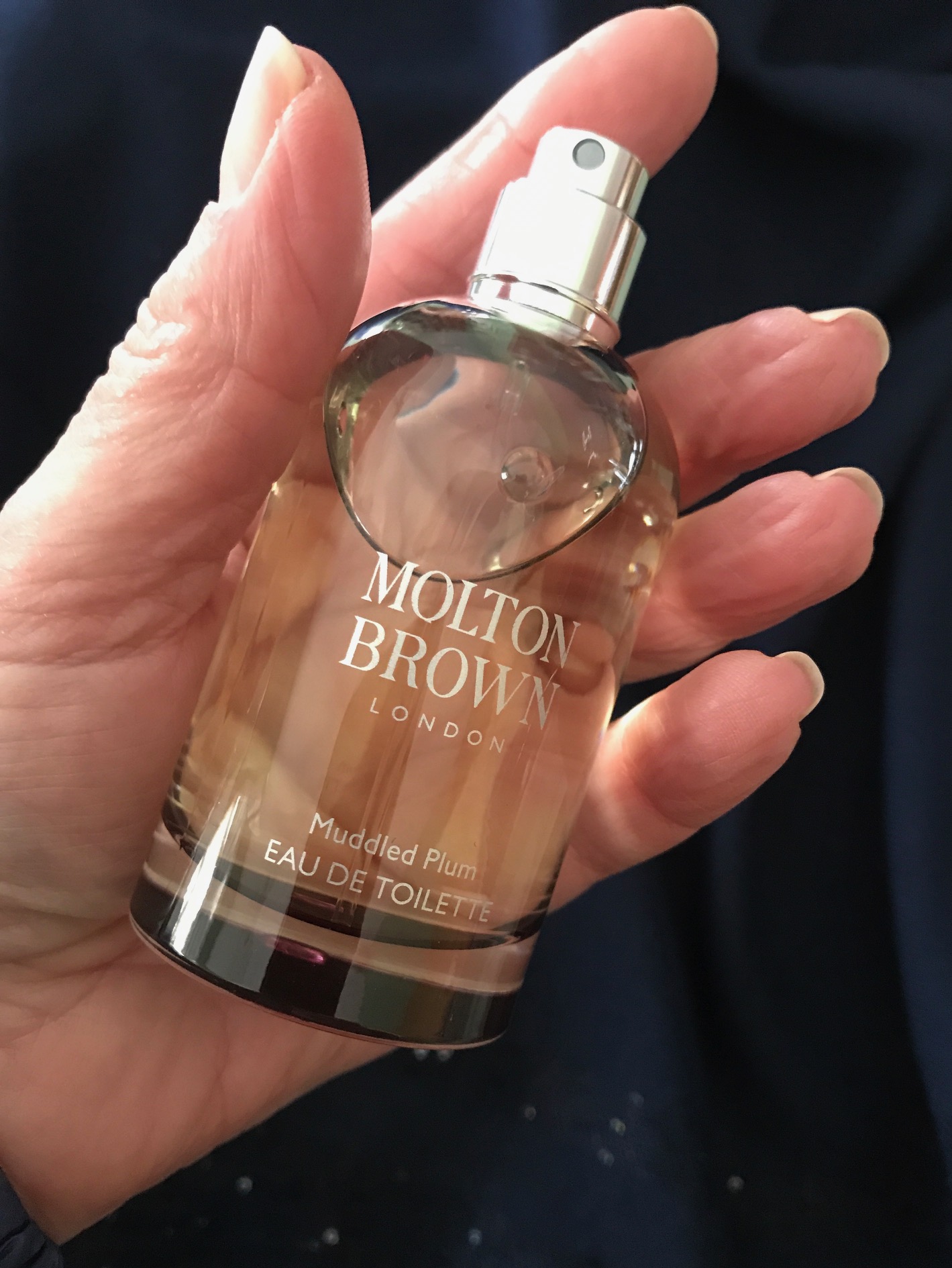 me holding the spray bottle of Molton Brown Muddled Plum eau de toilette, neversaydiebeauty.com